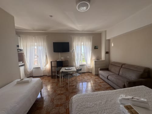 Habitación luminosa en B&B Falconara Marittima con camas, sofá, TV, comedor y vistas montañosas