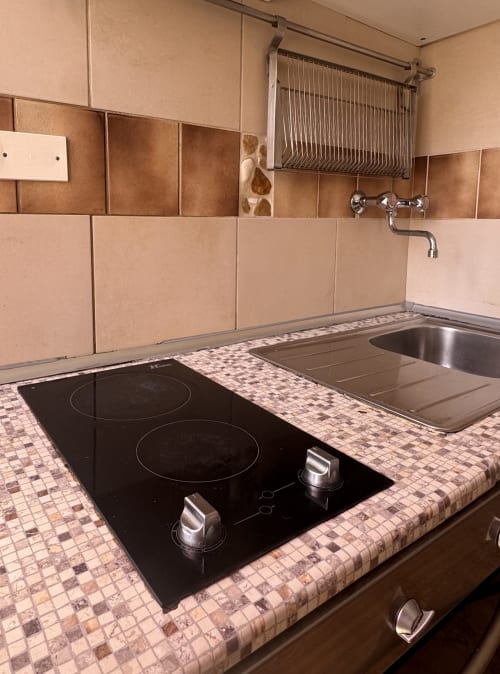 Área de cocina con estufa eléctrica, fregadero y encimera de azulejos mosaico en B&B Residenza Leonardo, Falconara Marittima