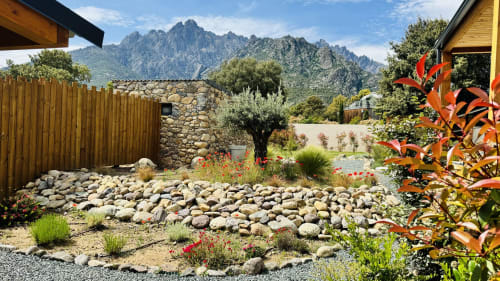 Villa Capu Biancu garden with stone patio, olive tree, and mountain views in Moltifao, Corsica