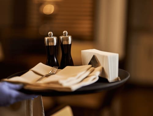 Elegant table setting at Palazzo Garibaldi Parma with napkins, cutlery, and salt and pepper shakers in warm lighting