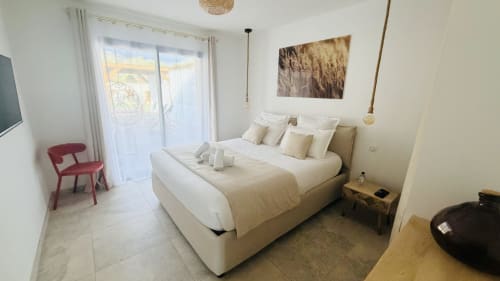 Modern bedroom in Villa Capu Biancu, Corsica with pool view, cream bedding and red accent chair