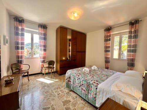 Luminosa camera Panorama di Casa Welcome Varigotti a Finale Ligure con vista mare, armadio in legno e tende rigate