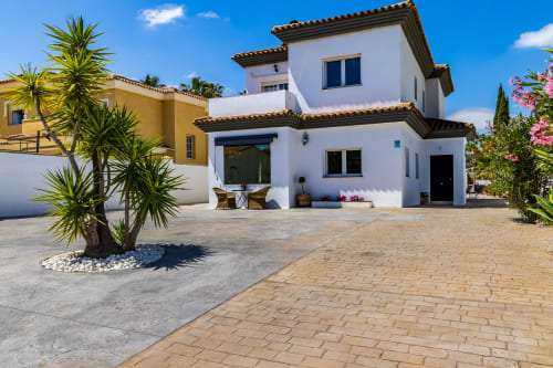 Villa Ayma Olsson en Alhaurín de la Torre: moderna villa blanca con terraza, palmeras y patio empedrado bajo cielo azul