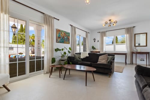 Amplio salón en Villa Ayma Olsson con sofá negro, mesa de café de madera y terraza con vistas a la piscina en Alhaurín de la Torre