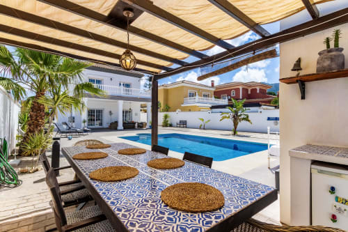Zona de comedor en terraza cubierta con vistas a la piscina azul de Villa Ayma Olsson en Alhaurín de la Torre