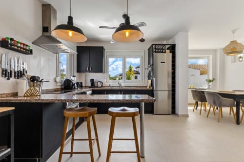 Cocina moderna en Villa Olsson Ayma, Alhaurín de la Torre, con muebles negros, encimeras de granito e iluminación colgante