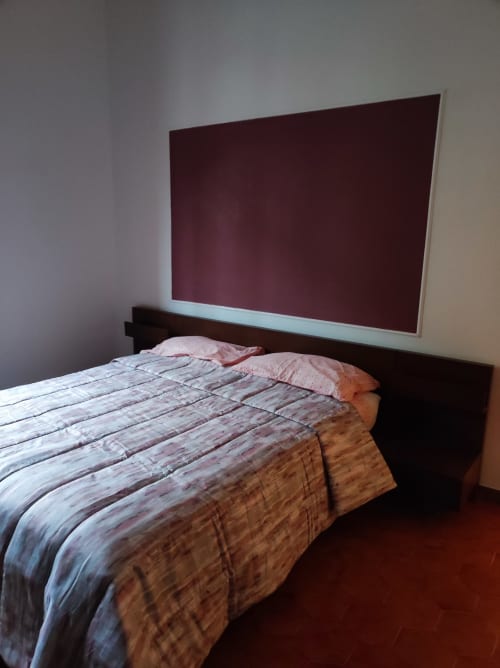 Camera moderna dell'hotel GRUPPO PLATONE ad Alessandria con letto in legno, biancheria a righe e pannello testata bordeaux
