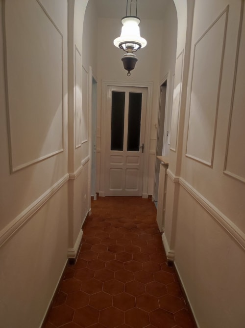 Elegante corridoio dell'appartamento Maison Platone Jolie ad Alessandria con pavimento in cotto e lampada a sospensione verso l'ingresso