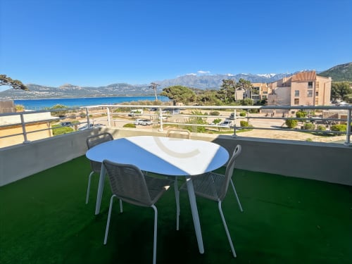 Terrasse ensoleillée avec table à manger donnant sur la mer Méditerranée bleue, les montagnes et le littoral de L'Île-Rousse