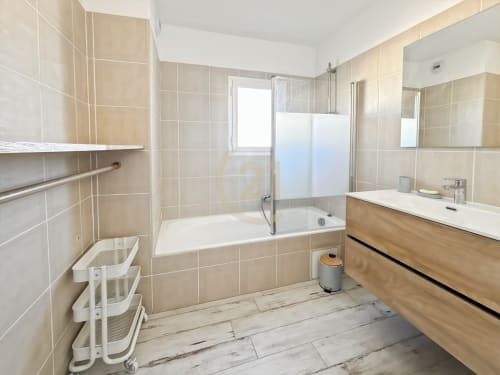 Salle de bain moderne avec carrelage beige, meuble-lavabo en bois, baignoire et douche à l'italienne vitrée à l'appartement de L'Île-Rousse
