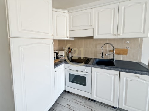 Cuisine blanche moderne avec plans de travail sombres et électroménagers en acier inoxydable dans l'appartement de L'Île-Rousse
