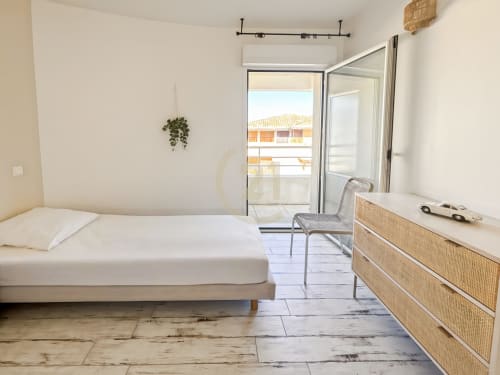 Chambre lumineuse avec vue mer à la Résidence Saint Philippe à L'Île-Rousse, lit, commode en rotin et accès balcon