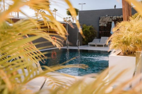 Piscine de l'Aevum Resort avec palmiers, transats et architecture moderne à Playa del Inglés