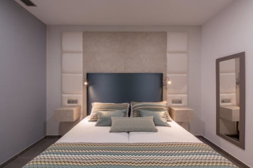 Modern suite bedroom at Aevum Resort with king bed, padded headboard, dual nightstands, and contemporary décor in Playa del