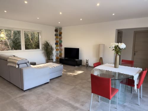 Modern villa living room with dining area, red chairs, white sofa, TV, and mountain views at In Casa Conciergerie, Figari