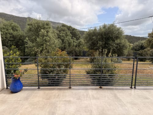 Terrace with metal railing overlooking olive groves and mountains at Villa A Santa, Figari