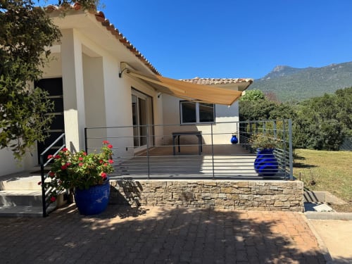 Modern villa A Santa with mountain views, stone terrace, retractable awning, and red flowers in Figari, France