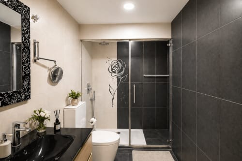 Baño moderno en apartamento Holibai con azulejos negros, lavabo flotante, ducha abierta y obra floral en Playa América