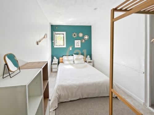 Chambre moderne avec mur d'accent bleu-vert, lit à baldaquin en bois, linge blanc et vue sur mer à L'Île-Rousse