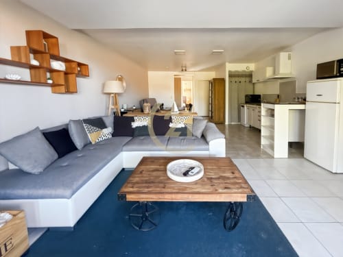 Séjour moderne à L'Île-Rousse avec canapé gris, table basse en bois, cuisine et accès à la vue mer