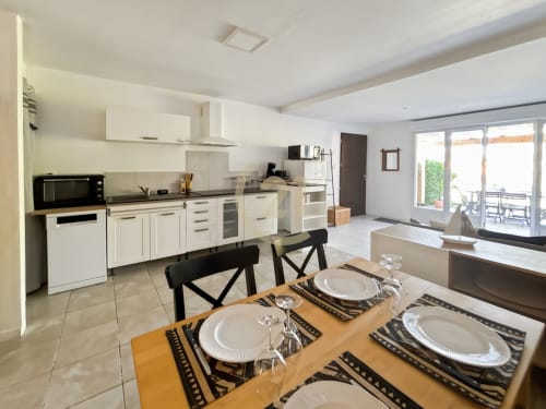 Cuisine ouverte moderne et salle à manger à L'Île-Rousse avec vue mer, placards blancs et accès à la terrasse