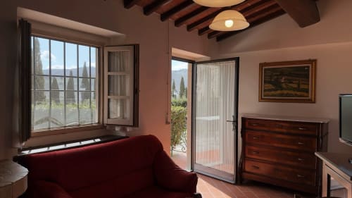 Accogliente soggiorno a Borgo di Erboli a Cavriglia con divano bordeaux, travi a vista e vista sulle montagne