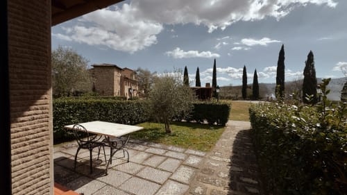 Terrazza della villa toscana a Borgo di Erboli con tavolo da pranzo, cipressi e vista sulla campagna a Cavriglia, Italia