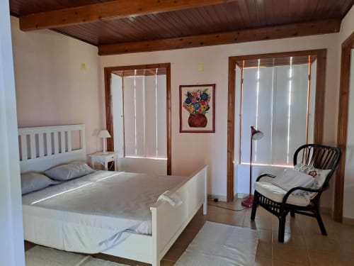 Bright villa bedroom at Inn Nature, São Roque do Pico with white bed, wooden beams, sea views, and modern amenities