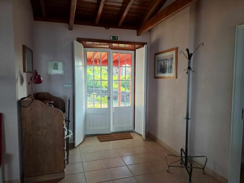 Bright entryway of O Abrigo villa at Inn Nature, São Roque do Pico, with glass doors opening to garden views