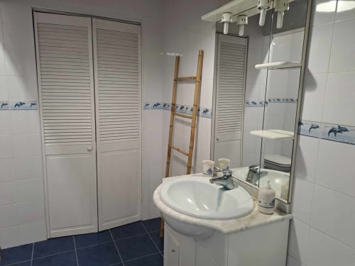 Modern bathroom at Inn Nature villa with round sink, mirror, shower enclosure, and blue-tiled floors in São Roque do Pico
