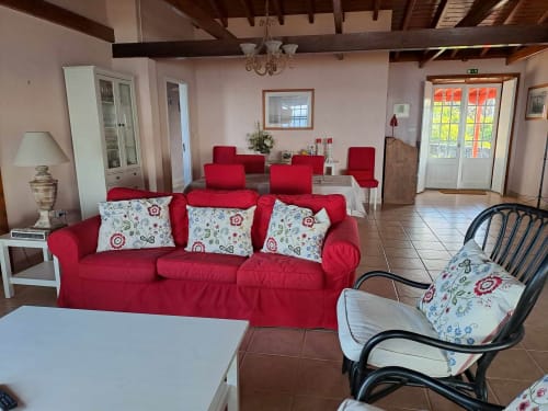 Red sofa with patterned pillows in O Abrigo villa lounge at Inn Nature, São Roque do Pico with sea views