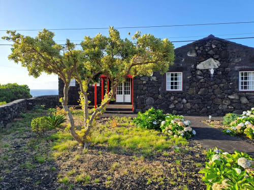 Black stone villa O Abrigo at Inn Nature in São Roque do Pico with garden, sea view, and red entrance