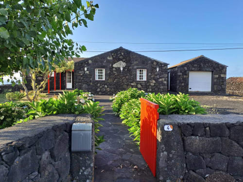 Stone villa O Abrigo at Inn Nature, São Roque do Pico, with red door and lush garden
