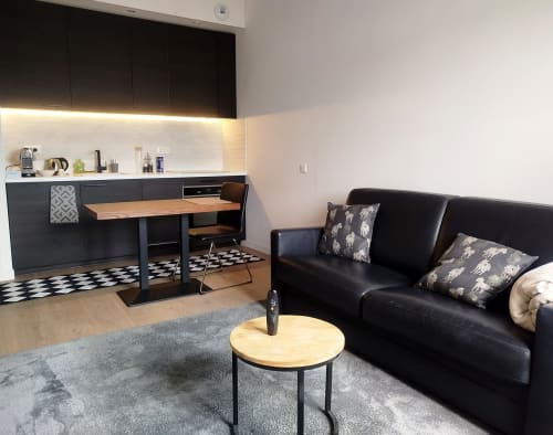 Appartement loft moderne à Villa Voltaire à Clamart avec cuisine noire, table à manger, canapé en cuir noir et table basse ronde