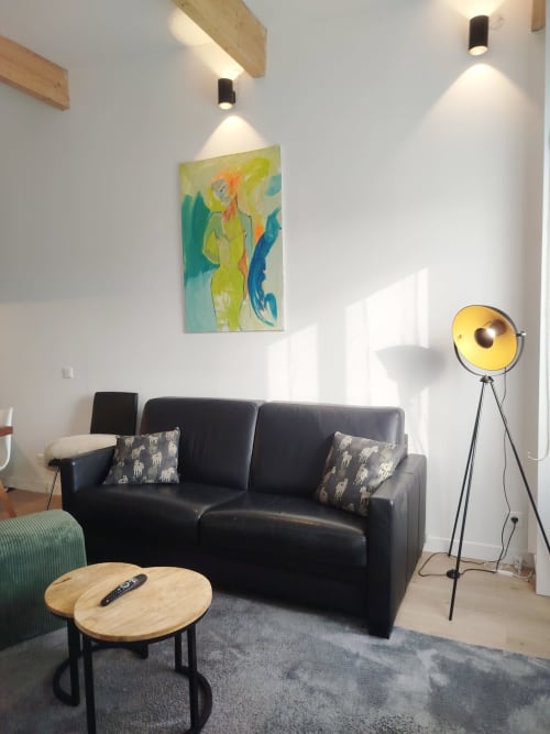 Élégant séjour de la Villa Voltaire à Clamart avec canapé noir, table basse en bois et lampadaire jaune tripattes