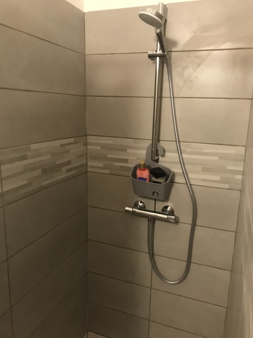 Modern shower corner with rainfall showerhead, handheld spray, and storage caddy at Beach House Fos guesthouse in Fos-sur-Mer