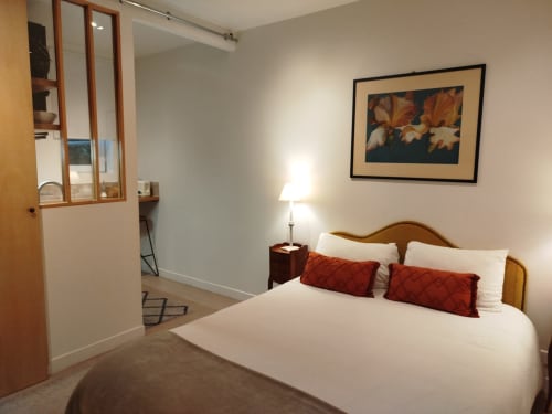 Chambre moderne à la Villa Voltaire, Clamart : lit en bois, oreillers rouges, linge blanc et toile iris encadrée