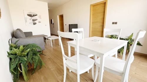 Estudio moderno en Dakar By Days con mesa de comedor blanca, sofá gris, pisos de madera y plantas verdes