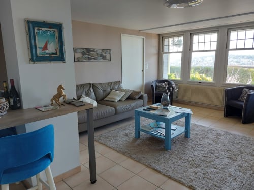 Séjour moderne à Aux Premières Loges à Fécamp avec canapé gris, table basse bleue et vue panoramique sur la mer