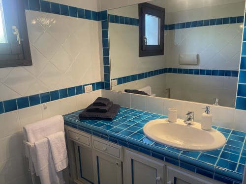 Modern bathroom with blue tile accents, oval sink, and bathtub at Like at Home Palau, Sea View Garden apartment in Palau,