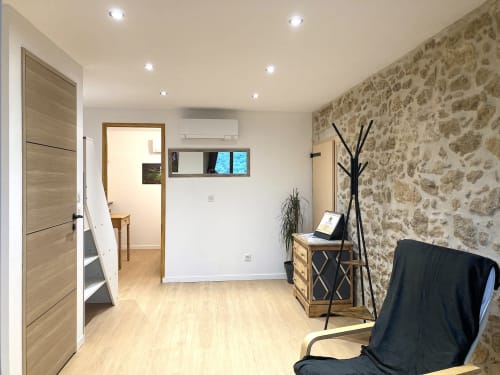 Suite moderna con pared de piedra, muebles de madera, escritorio con portátil y aire acondicionado en Au Château De Villelongue
