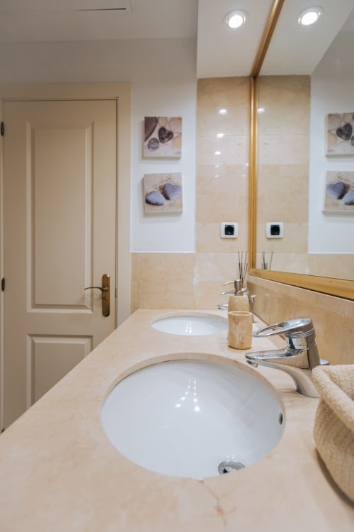 Modern bathroom vanity with dual sinks, marble countertop, and large mirror in Itaca apartment at BH Marbella hotel, Marbella