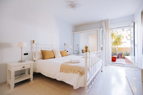 Bright modern bedroom at Itaca by BH Marbella with white metal bed, gold accents, and terrace with sea views