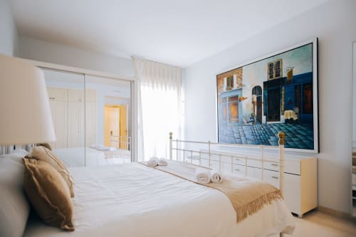 Modern bedroom at Itaca by BH Marbella with white bed, sea view artwork, and balcony access in Marbella