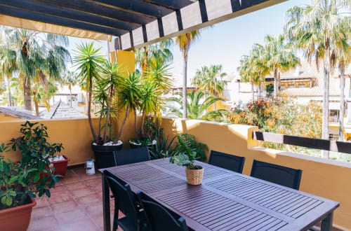Terrace at Itaca by BH Marbella with dining table, palm trees, and sea views in sunny Marbella