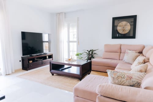 Modern living room at BH Marbella apartment with pink sofa, dark TV stand, and sea view balcony in Marbella