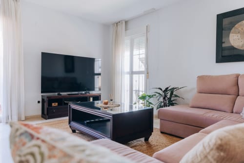 Modern living room at Itaca by BH Marbella with pink sofa, black TV stand, and balcony access to sea view