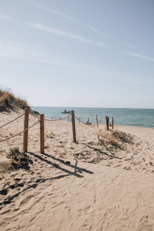 Sandy beach with wooden dune fence and sea view at Marbella coastal property, clear sky and turquoise water