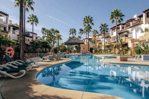 Luxury pool area at BH Marbella with loungers, palm trees, and Mediterranean-style architecture in Marbella