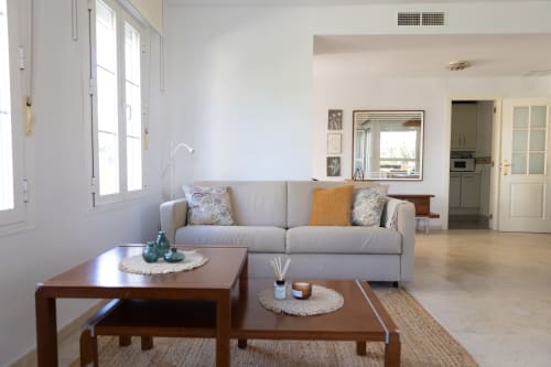 Modern living room with gray sofa, wooden tables, and garden views at Rodas by BH Marbella apartment, Spain